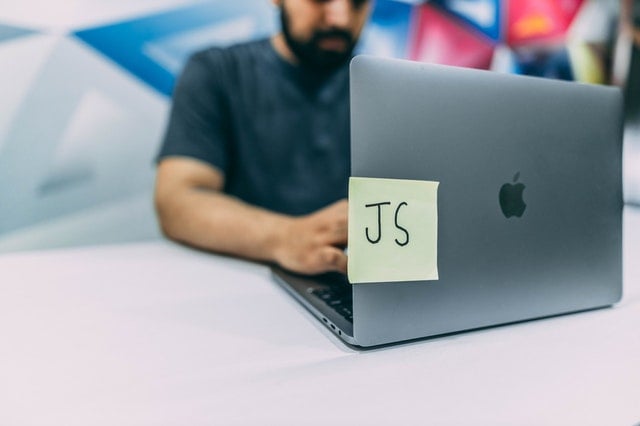 A JavaScript Developer working on a JavaScript project at a Macbook Pro